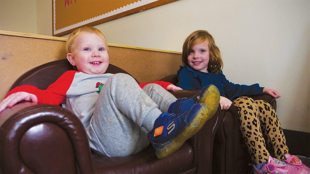 Boy and girl sitting in big leather chairs.